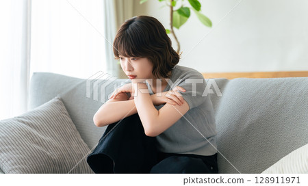 女人坐在客廳的沙發上思考 女人坐在客廳的沙發上思考 128911971
