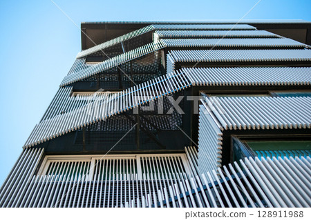 Modern Architectural Facade with Geometric Design and Blue Sky Modern Architectural Facade with Geometric Design and Blue Sky 128911988