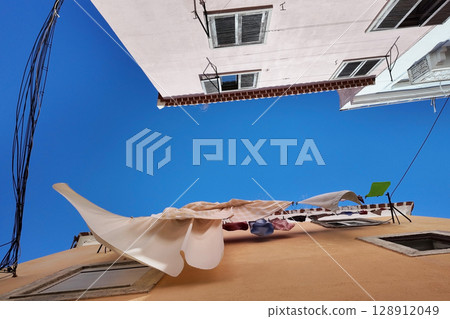Laundry Day Clotheslines and Buildings Against a Bright Blue Sky 128912049