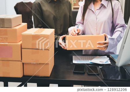 Portrait of Starting small businesses SME owners, two Asian woman check online orders Selling products working with boxs freelance work at home office, sme business online small medium enterprise Portrait of Starting small businesses SME owners, two Asian woman check online orders Selling products working with boxs freelance work at home office, sme business online small medium enterprise 128912206