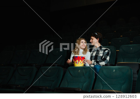 Young couple enjoys a movie night at the cinema with popcorn 128912603