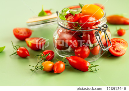 Fresh red and yellow tomatoes spilling from jar 128912646