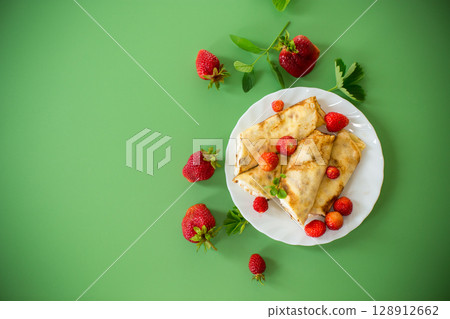Ukrainian pancakes with cottage cheese in a white plate on a green background Ukrainian pancakes with cottage cheese in a white plate on a green background 128912662