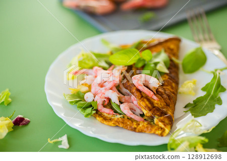 Appetizing breakfast omelette with shrimps and dill, on a green background 128912698