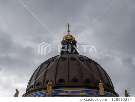 Berlin. Germany. 07.26.2025 A fragment of the dome of the Berlin Cathedral with a gilded cross against a cloudy sky. 128913234