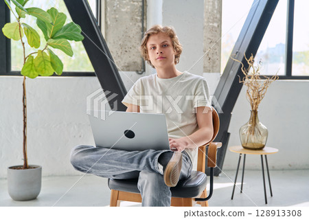 Portrait of teenage boy with laptop sitting at home Portrait of teenage boy with laptop sitting at home 128913308