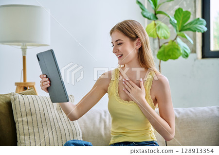 Young woman using digital tablet for video call, online chat conference sitting at home Young woman using digital tablet for video call, online chat conference sitting at home 128913354