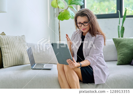 Middle aged woman working remotely, video conference, using digital tablet 128913355