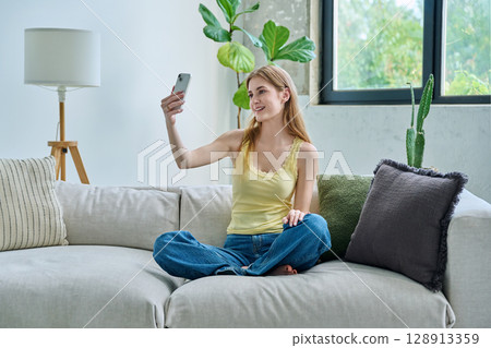 Smiling young teenage female taking selfie photo on smartphone Smiling young teenage female taking selfie photo on smartphone 128913359