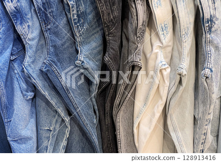 Many jeans hanging showing variety of colors washes and styles 128913416