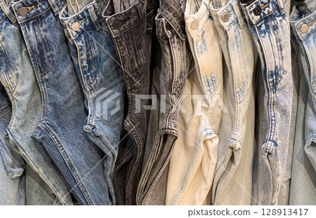 Many jeans hanging showing variety of washes and styles 128913417
