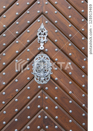 Old wooden door with metal decoration and rivets showing chevron pattern Old wooden door with metal decoration and rivets showing chevron pattern 128913469