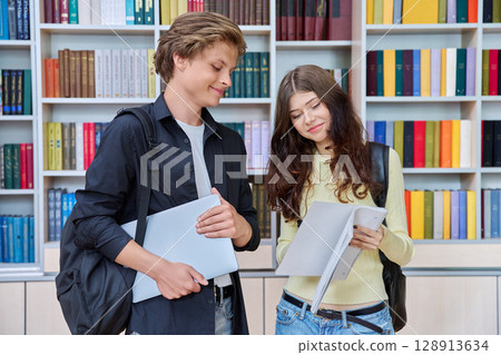 Portrait of two teenage students classmates boy and girl talking at school 128913634