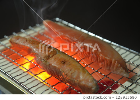 Grilling salmon on a charcoal grill with smoke rising Grilling salmon on a charcoal grill with smoke rising 128913680