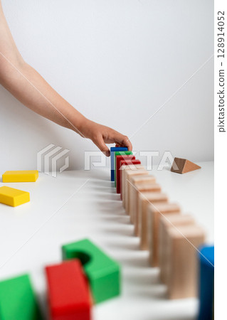 Child playing with colorful blocks in a creative domino setup 128914052