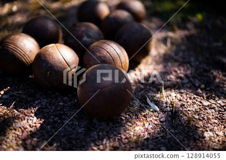 Vintage wooden bocce balls on gravel surface in sunlight 128914055