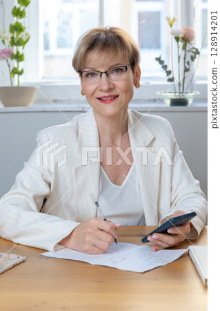 Portrait of business woman. Confident mature woman using mobile phone and typing. Vertical photo. High quality photo Portrait of business woman. Confident mature woman using mobile phone and typing. Vertical photo. High quality photo 128914201