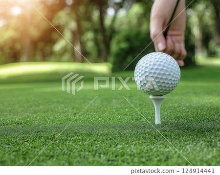 Golf ball on tee ready for a swing at a lush green course in the afternoon sun 128914441