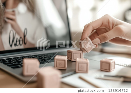 Creative person organizing pastel blocks on a laptop workspace with a clean aesthetic 128914712