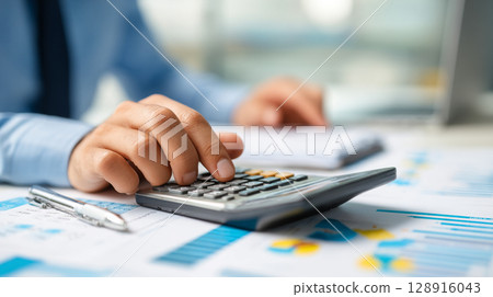 Businessman calculating with a calculator and financial documents 128916043