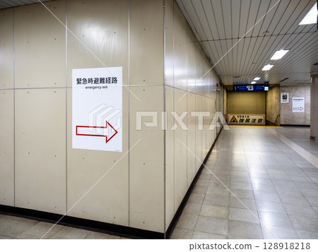 Emergency evacuation route signs posted in an underground train station 128918218