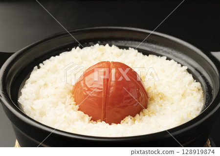 Whole tomato rice cooked in a steaming clay pot. 128919874