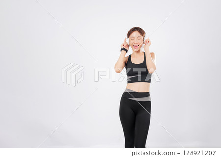Dance steps come alive as this Asian woman moves to her workout playlist. With every beat, her body flows in motion, and she continues to dance with freedom and joy. isolated studio white background Dance steps come alive as this Asian woman moves to her workout playlist. With every beat, her body flows in motion, and she continues to dance with freedom and joy. isolated studio white background 128921207