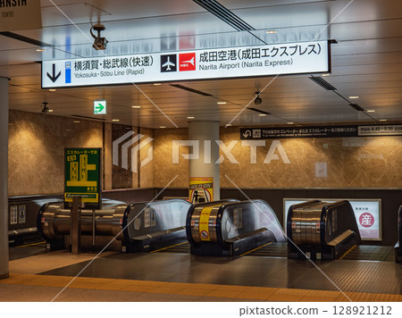 通往成田特快出發和到達月台的自動扶梯和標誌（JR東京站） 128921212