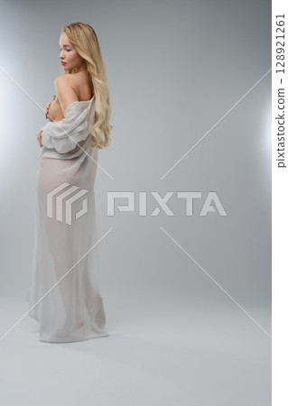 Blonde woman posing gracefully in a beauty studio with soft lighting 128921261