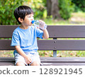男孩在公園長椅上喝水 128921945