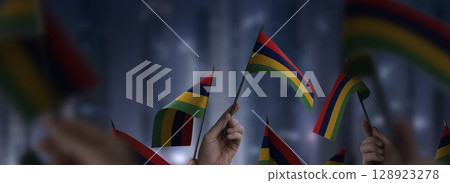 Mauritius flags in their hands on a blurred urban background 128923278