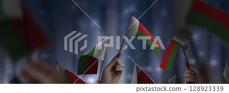 Madagascar flags in their hands on a blurred urban background 128923339
