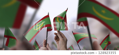 Mauritania flags in their hands on a blurred urban background 128923355