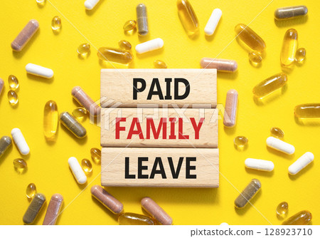 Paid Family Leave symbol. Concept words Paid Family Leave on wooden blocks. Beautiful yellow background with pills. Healthcare and Paid Family Leave concept. Copy space. 128923710