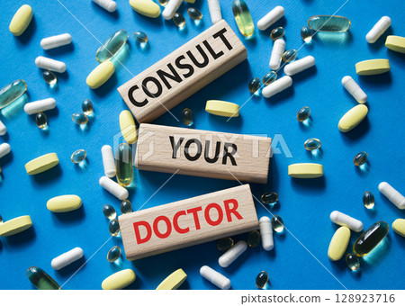 Consult Your Doctor symbol. Concept word Consult Your Doctor on wooden blocks. Beautiful blue background with pills. Medicine and Consult Your Doctor concept. Copy space Consult Your Doctor symbol. Concept word Consult Your Doctor on wooden blocks. Beautiful blue background with pills. Medicine and Consult Your Doctor concept. Copy space 128923716