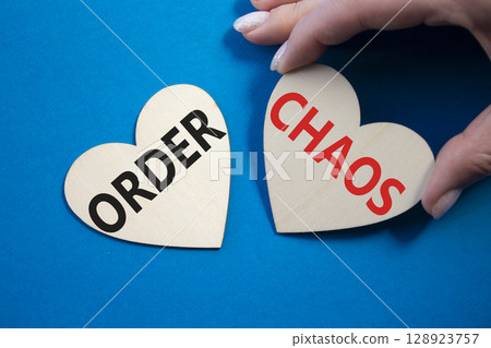 Chaos or Order symbol. Concept word Chaos or Order on wooden hearts. Businessman hand. Beautiful blue background. Business and Chaos or Order concept. Copy space 128923757