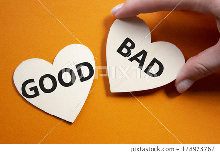 Good or Bad symbol. Concept word Good or Bad on wooden hearts. Businessman hand. Beautiful orange background. Business and Good or Bad concept. Copy space 128923762