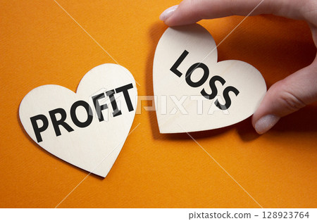 Profit or Loss symbol. Concept word Profit or Loss on wooden hearts. Businessman hand. Beautiful orange background. Business and Profit or Loss concept. Copy space Profit or Loss symbol. Concept word Profit or Loss on wooden hearts. Businessman hand. Beautiful orange background. Business and Profit or Loss concept. Copy space 128923764