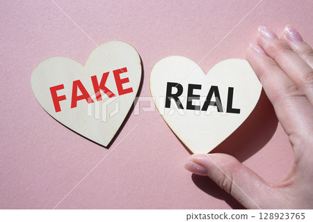 Real or Fake symbol. Concept word Real or Fake on wooden hearts. Beautiful pink background. Business and Real or Fake concept. Copy space 128923765