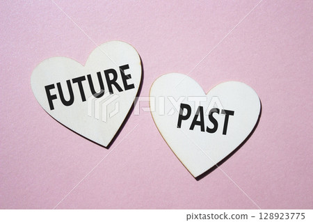Future or Past symbol. Concept word Future or Past on wooden hearts. Beautiful pink background. Business and Future or Past concept. Copy space 128923775