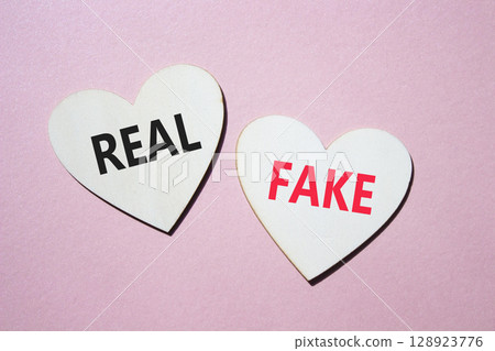 Real or Fake symbol. Concept word Real or Fake on wooden hearts. Beautiful pink background. Business and Real or Fake concept. Copy space 128923776