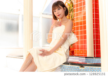 A woman in the bathroom wrapped in a bath towel 128925131