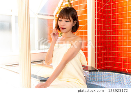 A woman in the bathroom wrapped in a bath towel 128925172
