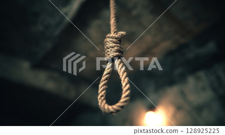 A chilling hangman's noose made of thick rope, hanging in a dark, ominous place. 128925225