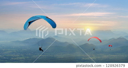 Paragliding in the sky. Paraglider flying over Landscape sun set Concept of extreme sport, 128926379