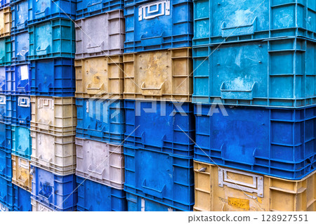 Stack of colorful plastic industrial crates arranged in a grid pattern for storage or transport use Stack of colorful plastic industrial crates arranged in a grid pattern for storage or transport use 128927551