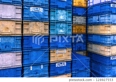 Stack of colorful plastic industrial crates arranged in a grid pattern for storage or transport use 128927553