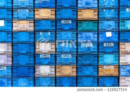 Stack of colorful plastic industrial crates arranged in a grid pattern for storage or transport use 128927554