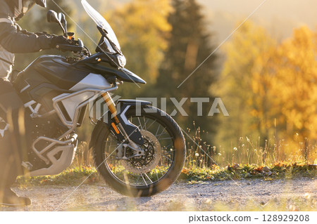 Driver posing on motorcycle during sunrise, rural countryside 128929208