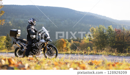 Driver posing on motorcycle during sunrise, rural countryside Driver posing on motorcycle during sunrise, rural countryside 128929209